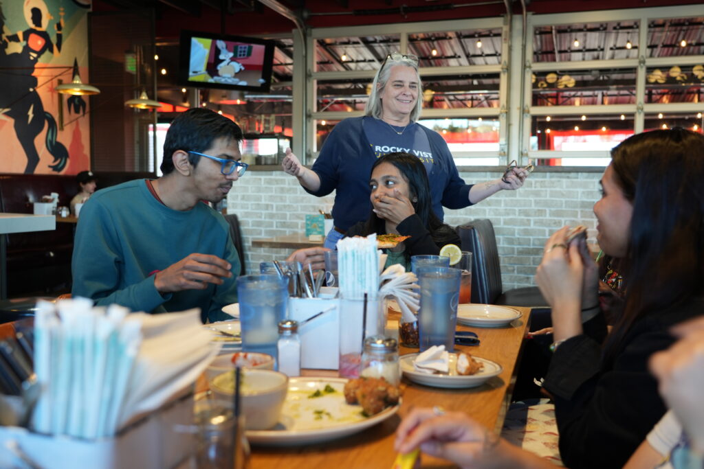 Candid shot of International students and Director of International Scholar Success talking over dinner