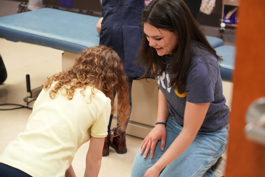 RVU student guides an elementary student through CPR training.
