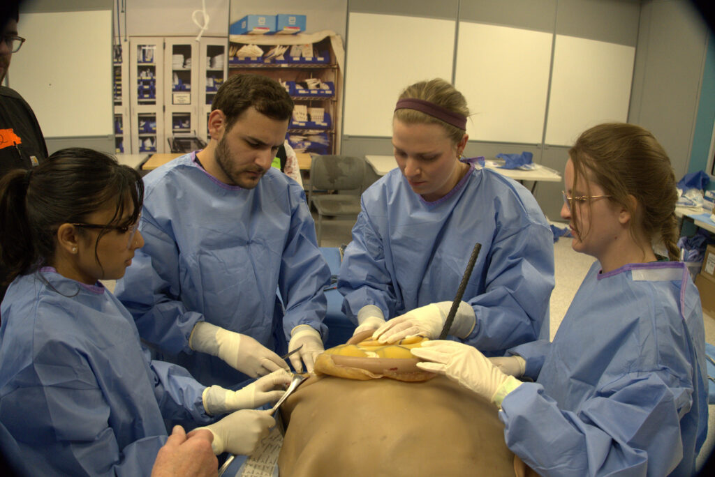 RVU students perform a simulated surgery on a surgical cut suit.