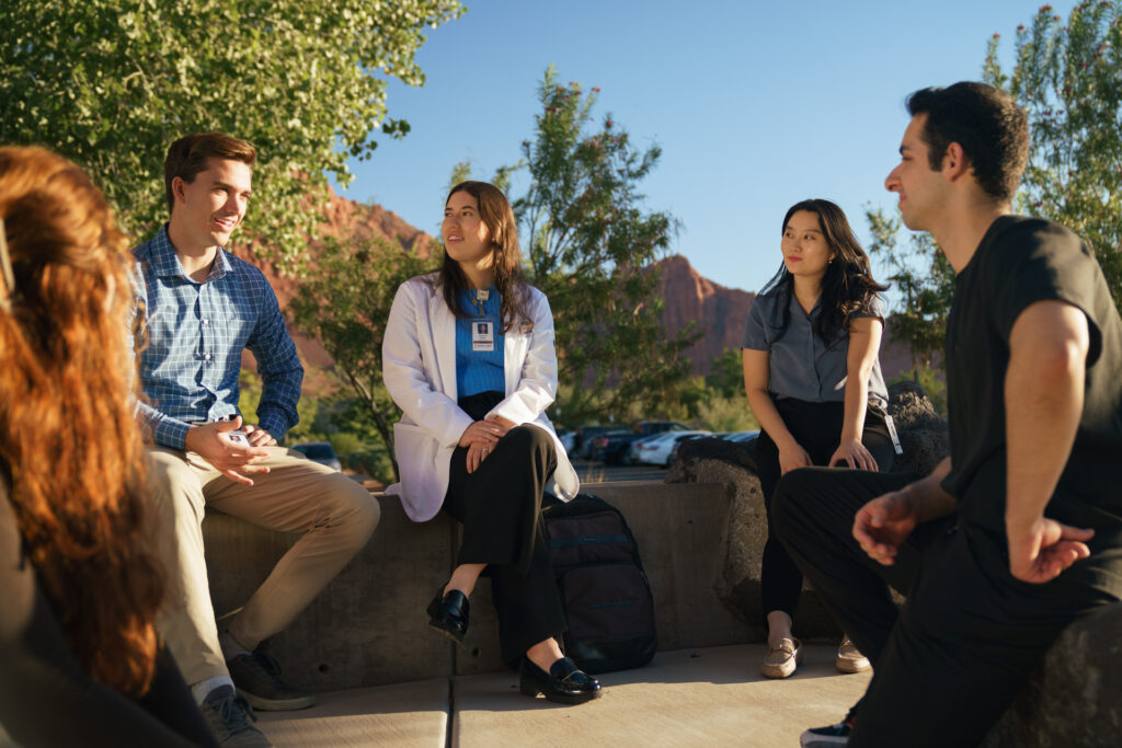 Group of students sitting outside talking with each other.