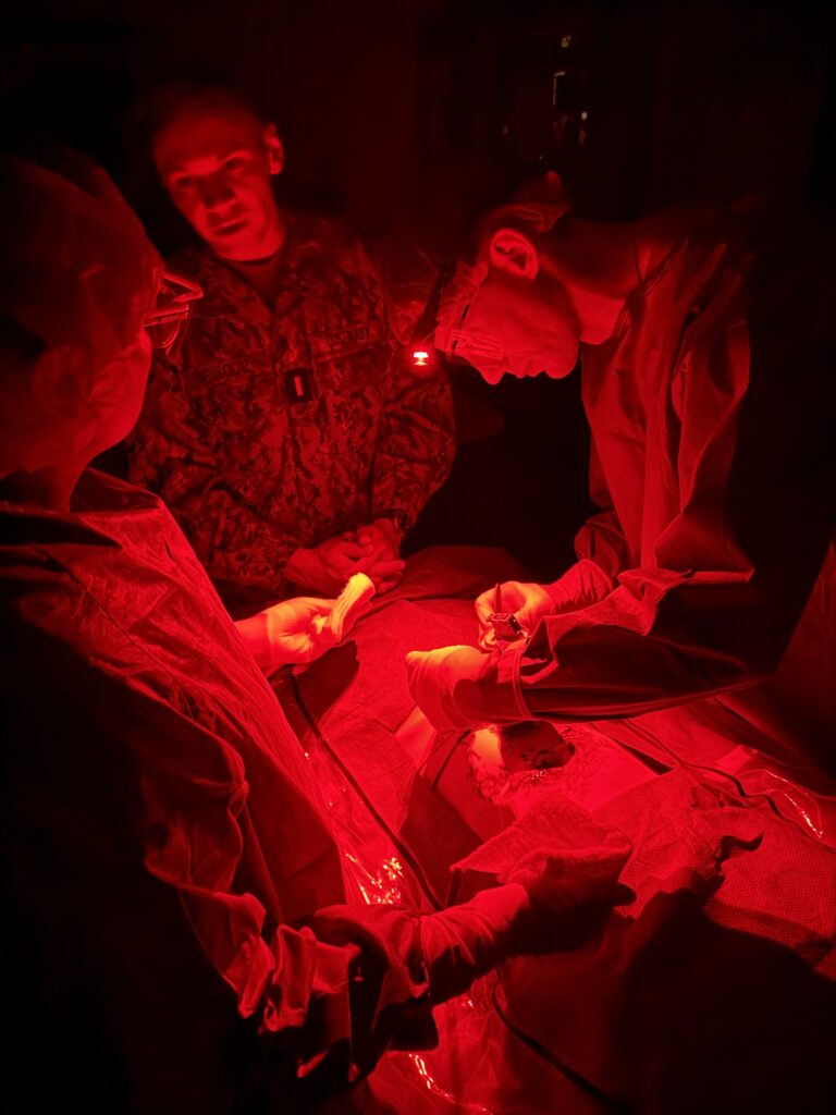 RVU students perform a simulated surgery using red-light head lamps.